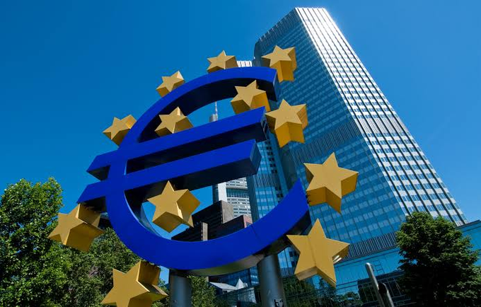 The iconic blue and yellow Euro (€) sign sculpture in front of the European Central Bank building in Frankfurt, Germany.
