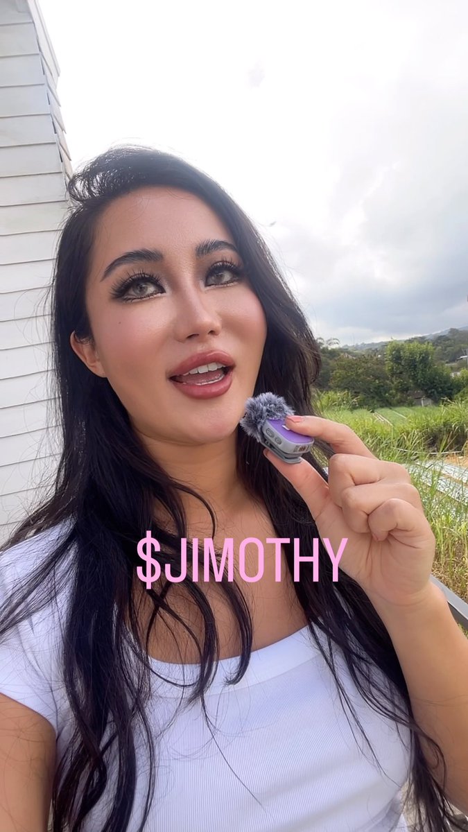 A selfie-style video frame of a woman holding a small purple recording device outdoors, with the text '$JIMOTHY' overlaid in pink.