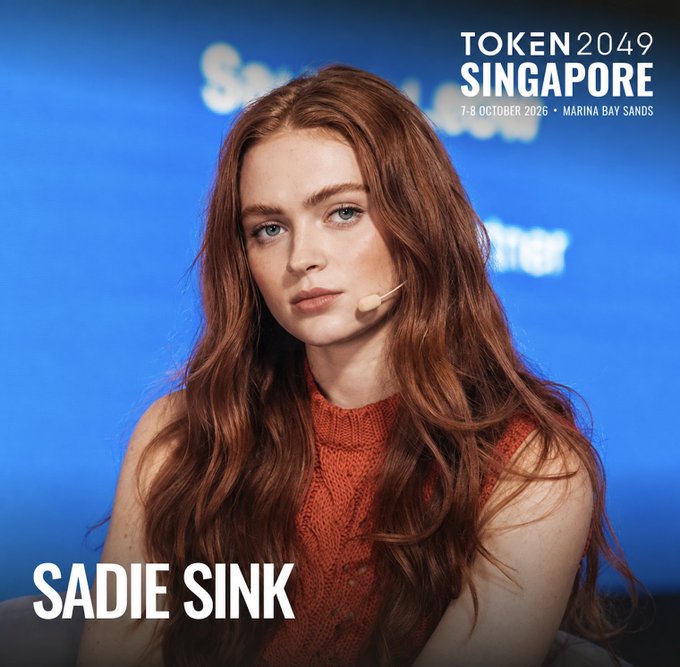 A promotional image for TOKEN2049 Singapore (7-8 October 2026, Marina Bay Sands) featuring Sadie Sink, a red-haired woman in a red sweater.