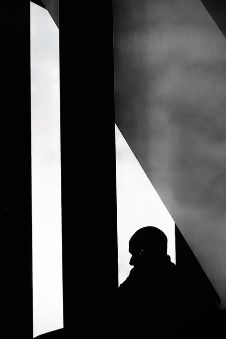 A silhouette of a person stands between stark geometric light panels in a high-contrast black and white composition, evoking the contemplative mood suggested by the artwork's title "Anchoring the Mind." The dramatic interplay of light and shadow complements the post's promotion of this piece from the @23ArtCollective, listed as edition 5/10 on objkt.com.