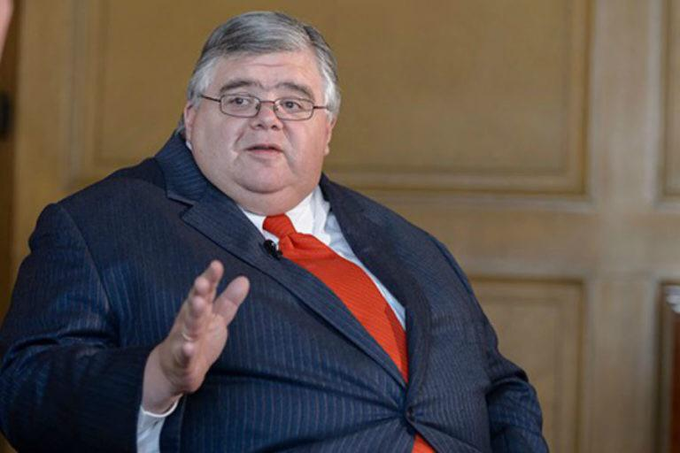 A bespectacled man in a dark pinstripe suit and red tie gestures while speaking, likely delivering a presentation or interview. The image pairs with a quote attributed to @saylor discussing Bitcoin's lack of a spam problem and its UTXO set, suggesting he is the speaker pictured.