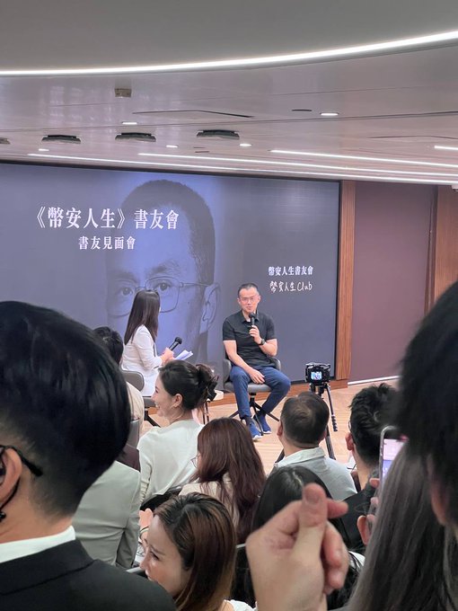 A book fan meeting event titled '《幣安人生》書友會' (Binance Life Book Club), with the book's author Robert (CZ-related content) seated on stage being interviewed by a host.
