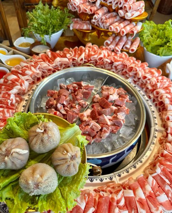 iced seafood and meat dishes, including shrimp, scallops, and ribs, are arranged on a table with ice and silverware.