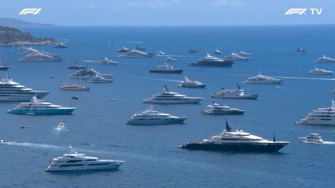 The image shows a large body of water with numerous boats, including luxury yachts and sailboats. The boats are scattered across the water, creating an impressive scene. In the background, there's a TV screen displaying two different images - one showing a yacht race on television and another showing a yacht in the ocean. The text "10 of these yachts belong to the cabal that’s been printing infinite zcash the past 4 years" is also present in the image. This suggests that the boats are part of an exclusive yacht club or organization, possibly involved in illegal activities such as money laundering and tax evasion.