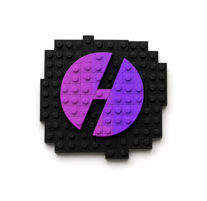 A 3D-rendered LEGO-style logo featuring a purple-to-pink gradient 'A' symbol constructed from interlocking studs, set against a black studded background.