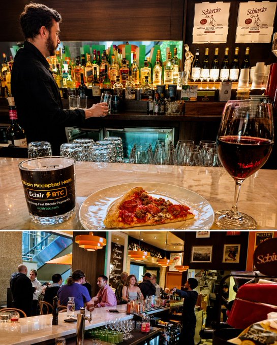 iced tea, pizza with red sauce and cheese on a white plate, wine glass filled with red wine, and a bar scene with people seated at tables and a bartender behind the counter.