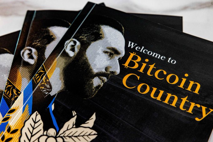 A promotional poster or magazine cover featuring a stylized image of a man and the text "Welcome to Bitcoin Country" in white and yellow lettering.