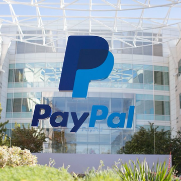 The image shows the PayPal corporate headquarters building with its large blue "PayPal" logo displayed on the glass facade. The image directly relates to the news of PayPal expanding its PYUSD stablecoin onto the Polygon network.