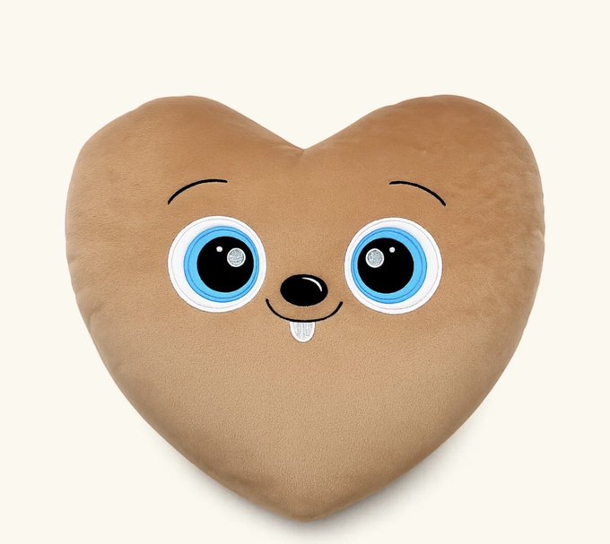 A brown heart-shaped plush toy with large blue cartoon eyes and a cute smiling face sticking out its tongue.