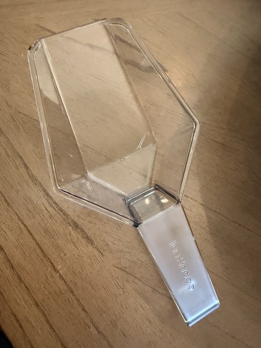 A clear plastic and silver bottle stopper labeled 'ProKeeper' lying on a wooden surface.
