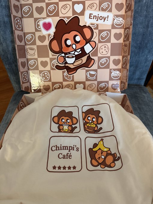 An open box featuring cute monkey illustrations with the text 'Enjoy!' displays a wrapped item labeled 'Chimpi's Café' with cartoon monkeys enjoying various snacks and drinks.