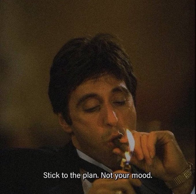 A cinematic still of a man in a dark suit lighting a cigarette with a gold lighter, with the subtitle 'Stick to the plan. Not your mood.'