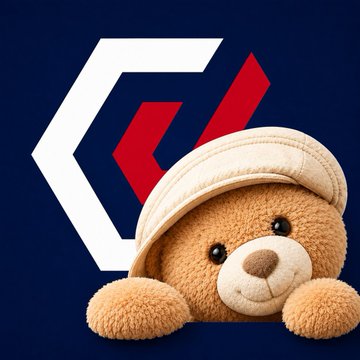 A close-up of a shiny, light-colored teddy bear wearing a beige cap, peeking out against a dark blue background with a white and red logo.
