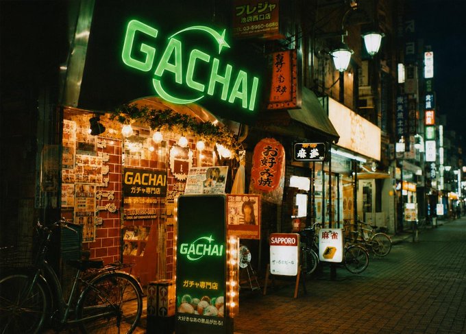 A nighttime photograph of a Japanese street featuring a restaurant named 'GACHAI' with a glowing green neon sign, Japanese lanterns, bicycles, and an adjacent Sapporo sign.