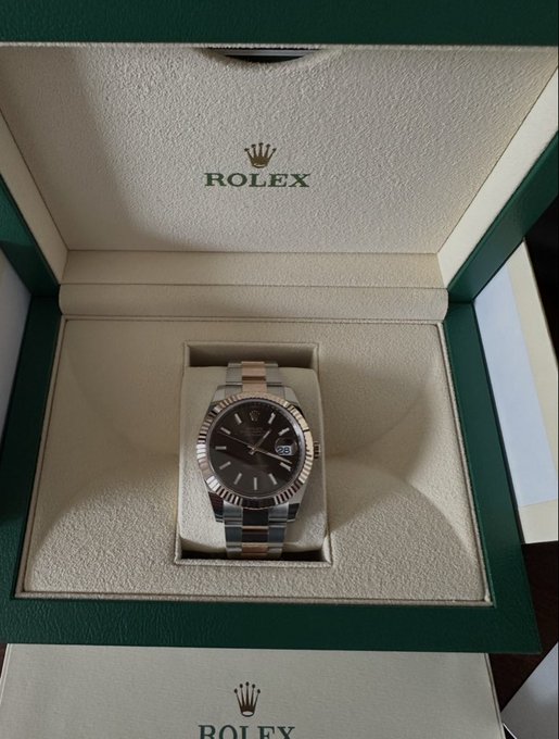 A Rolex Datejust with a black dial and two-tone (steel and gold) Oyster bracelet sits in its green Rolex presentation box, celebrating the owner's first Rolex purchase made possible by memecoin gains.