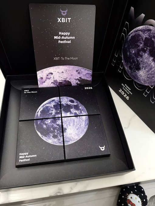 An open black gift box contains a card reading 'XBIT Happy Mid-Autumn Festival XBIT To The Moon' and a 2026 calendar featuring a large purple moon graphic divided into four panels.