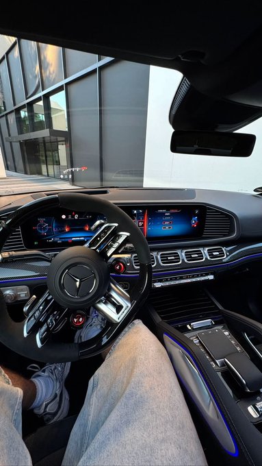 A view from the driver's seat of a Mercedes-Benz, showcasing the luxurious dashboard with digital displays and a sleek steering wheel, while the driver (wearing jeans and sneakers) extends their legs in a relaxed pose. The caption "Good morning CT Gm if you gm" complements the image's casual, morning vibe, inviting others to greet back.