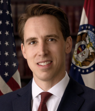 Portrait photograph of a man in a dark suit and red tie, identified as Senator Josh Hawley, standing in front of an American flag and a Missouri state seal.