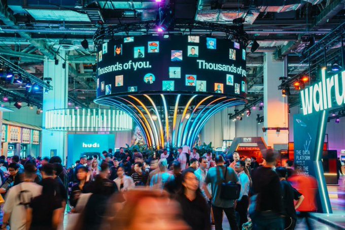 A crowded crypto conference floor features a large central display reading "Thousands of you" alongside app icons, with visible signage for "walrus," "huds," "5VIE," and "The Data Platform Built for the Real Economy" — imagery that contrasts with the post's claim that Sui's ecosystem lacks a real community, since this staged event presentation suggests manufactured hype rather than genuine organic participation.