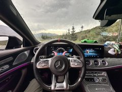 Interior view of a Mercedes-Benz car with a view of mountains and forest through the windshield.