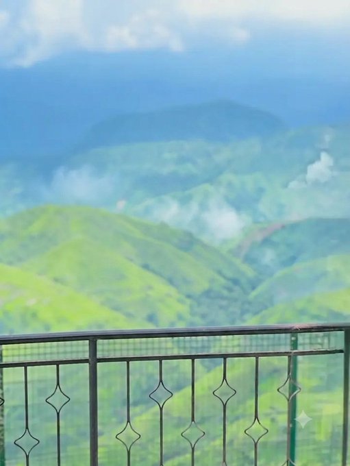 A scenic view from a balcony overlooking lush green mountains and valleys shrouded in mist, likely taken from a hill station or mountain resort, evoking a sense of exploration and adventure that complements the post's theme of ongoing exploration.