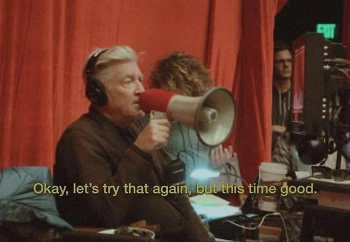 A still from a film or show showing an older man with headphones speaking into a megaphone, with the subtitle 'Okay, let's try that again, but this time good.'