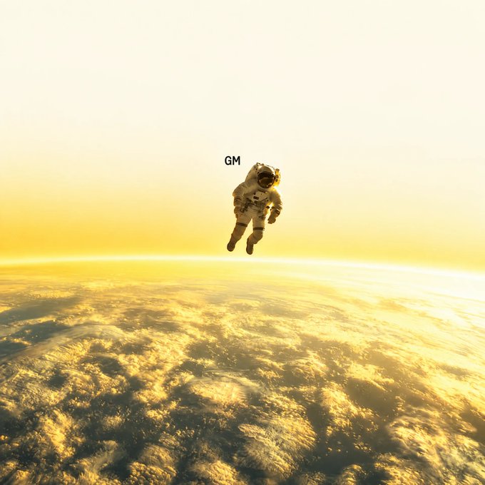 An astronaut floats above Earth's cloud-covered horizon in a golden-hued atmosphere, with the letters 'GM' (good morning) displayed near their head.