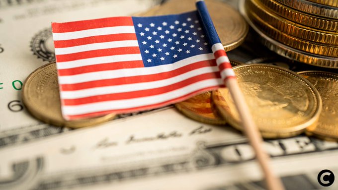 A small American flag rests atop stacks of gold coins and U.S. dollar bills, symbolizing the financial stakes of the upcoming CLARITY Act Senate vote.