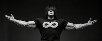 A black and white photo shows a muscular man with long hair flexing his arms outward, wearing a t-shirt featuring the infinity symbol (∞). The image is used to represent the endless potential of profiting from copy trading, visually emphasizing the post's message about a copyfomo follower who reportedly turned a $500 trade into significant gains by following wallet "Rowdy" into $DOPE on Solana.