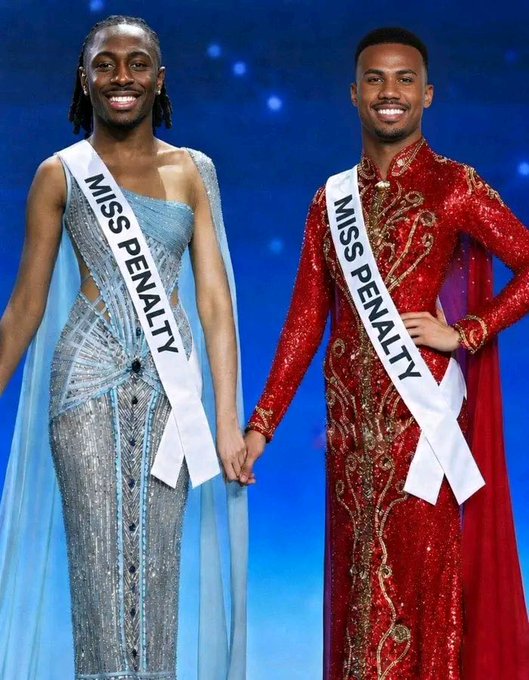 The image features two men wearing red dresses, standing side by side with smiles on their faces. The man on the left is dressed in a blue dress, while the other man wears a red one. They are both smiling at the camera, showcasing their outfits and possibly participating in an event or competition that requires them to wear such attire. The image also includes text that reads "Miss Penalty" and "wallchain @ wallchain", which could be related to a specific theme or context of the event they are attending.