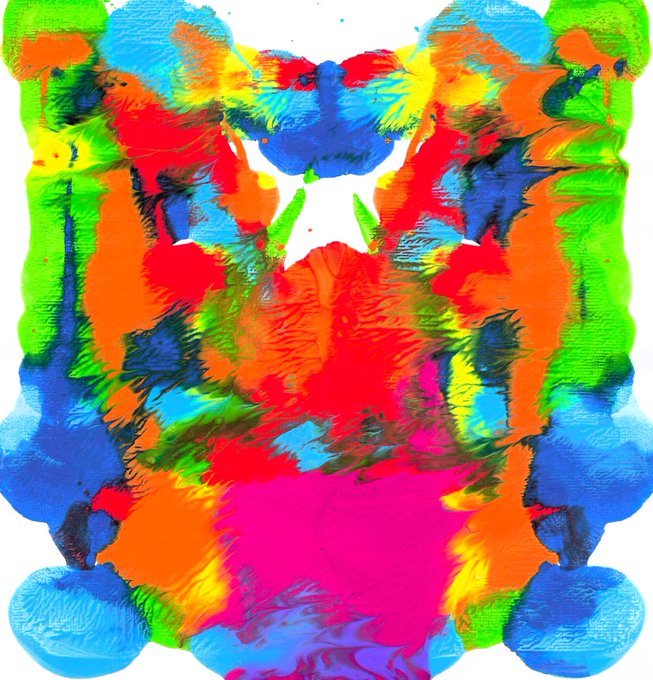 A symmetrical Rorschach-style inkblot artwork bursting with bright neon colors like blue, pink, red, orange, and yellow.