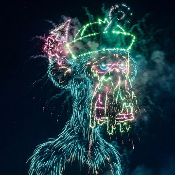 A neon-colored light-painting image of a gorilla wearing sunglasses and a party hat against a dark background.