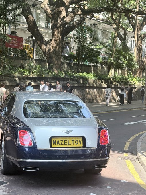 A luxury car parked on a street with a license plate reading 'MAZELTOV'.
