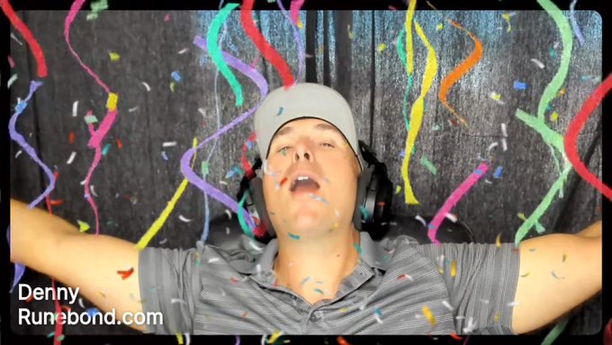 A man wearing a white beanie and headphones celebrates with arms raised as colorful confetti and streamers fall around him, with text 'Denny Runebond.com' in the corner.
