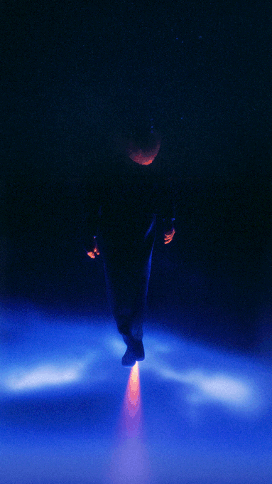 The image shows a person walking across a blue surface with their arms outstretched. The background of the photo is dark, creating an atmosphere of mystery or intrigue. There are no other objects or people visible in the image, which adds to its sense of solitude. The caption "Symmetrical directional noise. A solitary figure." suggests that this scene might be inspired by a surreal or dreamlike setting.