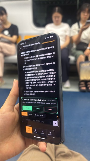 A person holds a smartphone showing a Korean article and code snippet on a CLI tool 'gigit', with an APK code redemption interface visible, while sitting on a subway with passengers in the background.
