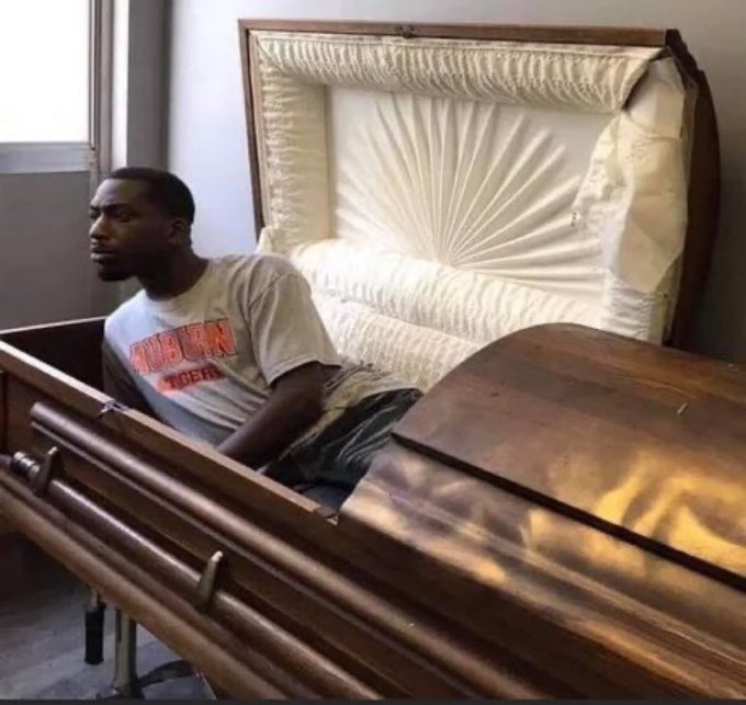 The image features a man sitting inside an open wooden casket, which appears to be made of wood and has a white interior. The man is wearing a gray t-shirt with "Bam! BAM!" written on it. The caption below the image reads "When $XRP finally breaks thru resistance".