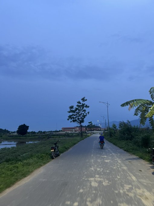 The image shows a road with two people riding bicycles, one closer to the foreground and another further back. There are also motorcycles parked along the side of the road. The sky above them appears cloudy, suggesting an overcast day. In the background, there is a building that could be a house or a residential area. The post "GM CT Hello web3" seems to be related to the image in some way, possibly indicating a connection between the people riding bicycles and the motorcycle owners, or it might be a part of the website's content about cycling or transportation.