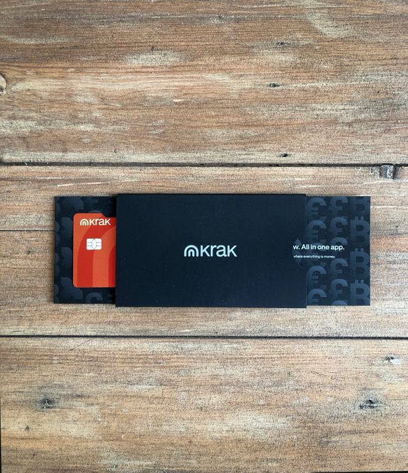 A sleek black Krak debit card with a red EMV chip peeks out from its branded packaging sleeve on a rustic wooden surface, displaying the tagline "w. All in one app." The unboxing complements the post's praise for Krak's smooth product experience, hinting at the exciting upgrade to the upcoming metal card.