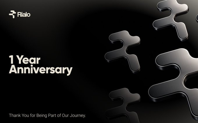 A promotional graphic for "Rialo" celebrating its "1 Year Anniversary" with the message "Thank You for Being Part of Our Journey," set against a dark background with glossy 3D puzzle piece elements.