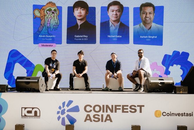 A panel of four speakers sits on stage at Coinfest Asia, with the event branding and sponsors ICN and Coinvestasi visible. A screen above displays headshots and titles for moderator Kevin Susanto, Gabriel Rey (Founder & CEO), Nichel Gaba (CEO), and Ashish Singhal (CEO).