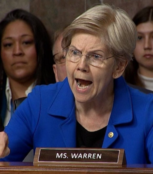 Senator Elizabeth Warren, identified by a "MS. WARREN" nameplate, speaks forcefully at a hearing, aligning with her stated opposition to the Clarity Act, which she warns poses massive risks to families, national security, and the economy.