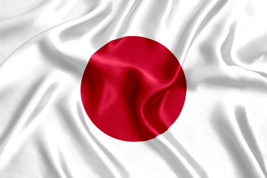 The image shows the flag of Japan—a white field with a central red circle—rendered in flowing, satin-like fabric. It visually represents Japan's national identity, complementing the news about SBI Group's partnership with Ondo Finance to tokenize Japanese stocks and bring the country's equities onchain.