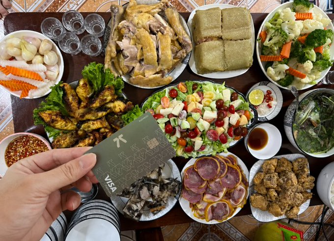 The image shows a table filled with various types of food, including meat, vegetables, and salad. A person's hand is holding a Visa card over the table, suggesting that they are using the card for payment at this gathering. The post about crypto payment solutions emphasizes how easy it can be to use digital assets like Bitcoin or other cryptocurrencies in everyday life, even when making payments at social events such as parties or gatherings.