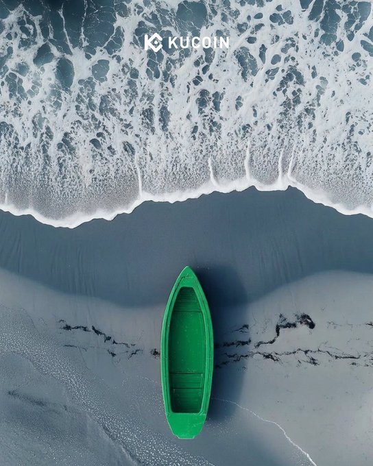 An aerial view shows a green rowboat beached on the shore as foamy ocean waves roll in, with the "KUCOIN" logo displayed at the top. The green boat visually reinforces the caption's "green wave" metaphor, tying the natural scene to cryptocurrency market momentum.