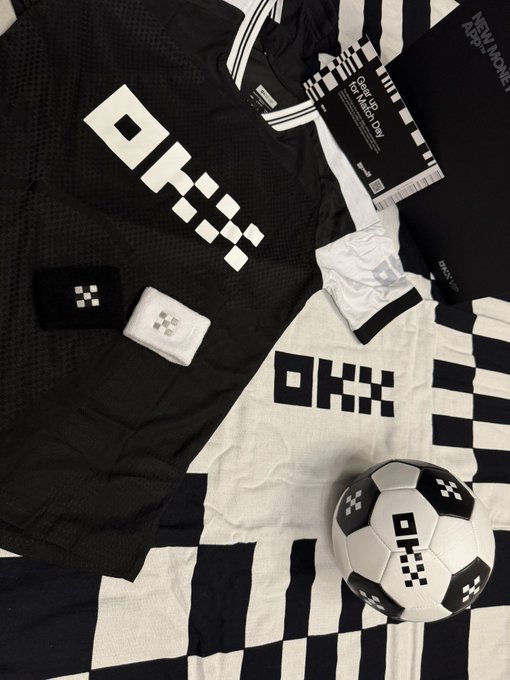 The image features a soccer ball with black and white designs, surrounded by various items such as a t-shirt, shorts, socks, and a towel. The objects are arranged in a way that suggests they belong together or are part of a sports team's gear. The presence of these items indicates the importance of sports equipment for athletes, particularly those who play soccer.