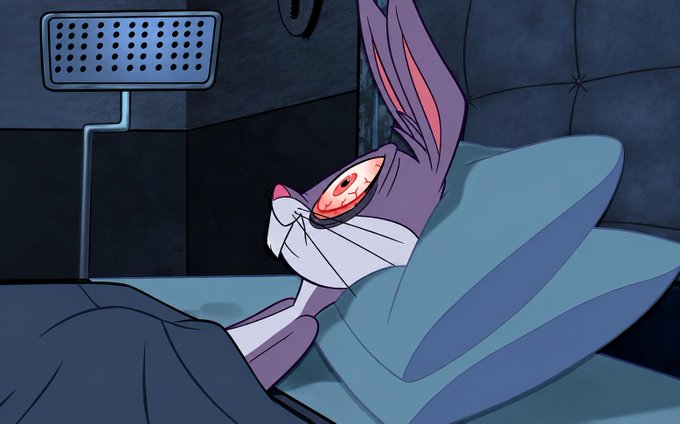 A screenshot from an animated cartoon featuring the character Bugs Bunny lying in a bed, looking wide-eyed and alert.
