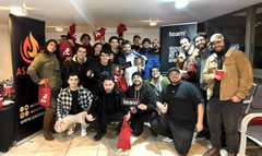 A blurred group photo captures a lively Watch Party gathering, with attendees posing together for a commemorative shot. A sign reading "THAI" is partially visible on the wall behind the crowd, reflecting the social atmosphere of the AvaxTeam1 community event.