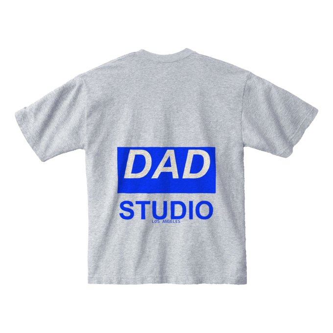 A heather gray T-shirt displayed flat from the back, featuring a blue rectangular logo with "DAD" in large white letters and "STUDIO LOS ANGELES" printed below, representing the DadStudio web3 art brand mentioned in the accompanying testimonial post.