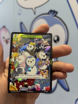 A hand holds a holographic Pokémon trading card featuring a Pippychu character, held up against a backdrop of Comic Con signage and a Pudy Penguins mascot. The card appears to be a custom or fan-made "Speedy Strike" themed collectible from the @vibes_tcg booth at Comic Con, displaying text about an attack that "does 30 damage" and "Choose 1 of your Pokémon... put 6 damage counters on it."